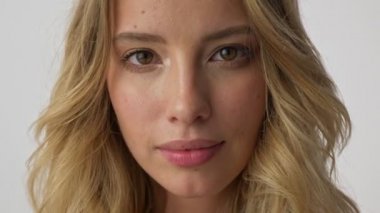 Gri arka plan izole üzerinde kameraya bakarken gülümseyen neşeli genç sarışın kadın Kırpılmış görünümü