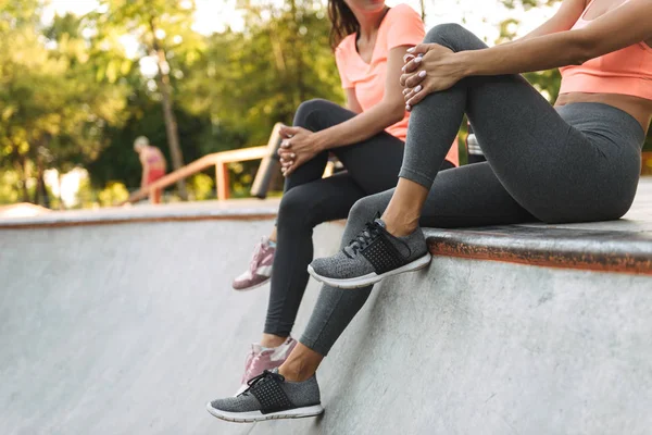 Bild von jungen schlanken Frauen, die auf Betonsportplatz sitzen und reden — Stockfoto