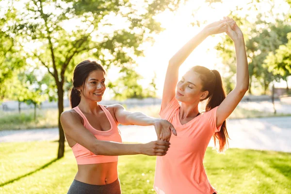 Beeld van mooie fitness vrouwen in sportkleding doen trainen in Green Park in de ochtend — Stockfoto