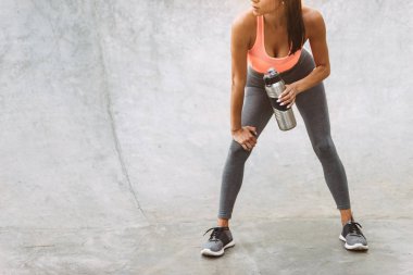 Beton spor zemin açık havada su şişesi tutan odaklanmış genç kız Kırpılmış görüntü