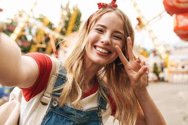 Beeld van jonge blonde vrouw tonen vredesteken en het nemen van selfie — Stockfoto
