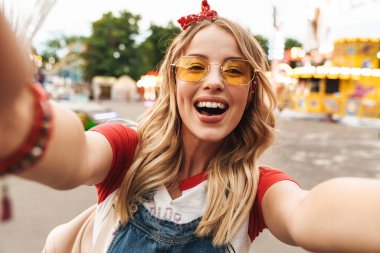 Sevimli sarışın kadının gülme ve selfie fotoğrafı çekmesi görüntüsü 