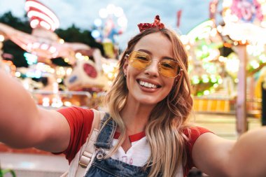 Genç sarışın kadının gülme ve selfie fotoğrafı çekerken görüntüsü 