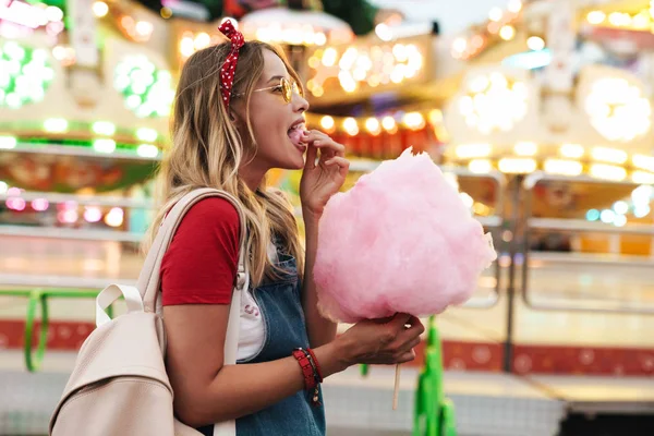 Beeld van mooie schattige vrouw het eten van zoete suikerspin terwijl walki — Stockfoto