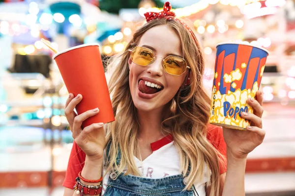 Зображення щасливої чарівної жінки, що тримає попкорн і чашку паперу з содовою — стокове фото