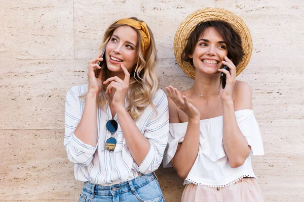Glimlachend gelukkig vrolijke positieve jonge vrouwen vrienden buitenshuis praten met mobiele telefoons. — Stockfoto