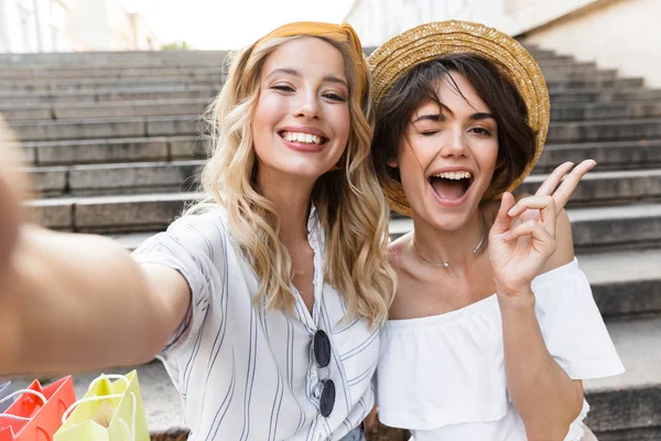 Sonriendo lindas chicas jóvenes amigos al aire libre en los pasos tomar una selfie por la cámara . — Foto de Stock