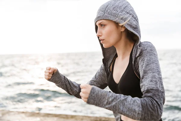 Afbeelding van serieuze blonde vrouw boksen tijdens het trainen op de pier in de buurt van de kust in de ochtend — Stockfoto