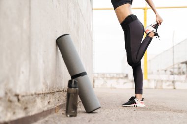 Bir duvara yaslanmış genç bir fitness kız Kırpılmış görüntü