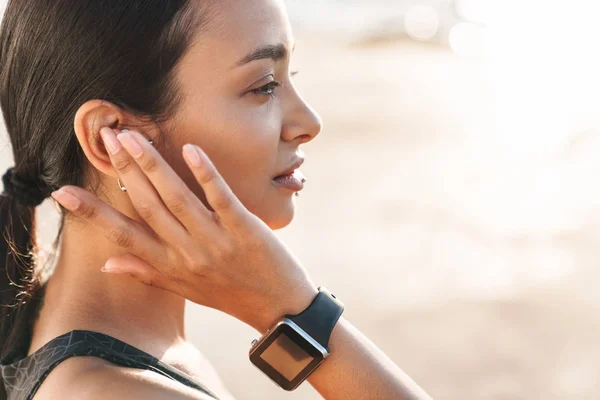Konzentrierte junge, kräftige Fitness-Frau am Strand, morgens Musik mit Kopfhörern hörend. — Stockfoto