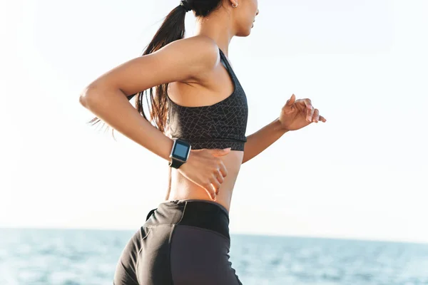 Erstaunliche junge starke Fitness-Frau im Freien am Strand beim morgendlichen Laufen. — Stockfoto