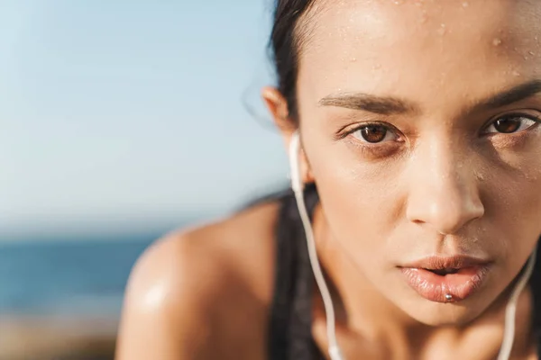 Grave bella giovane donna sportiva forte all'aperto in spiaggia al mattino hanno un riposo ascoltare musica con gli auricolari . — Foto Stock