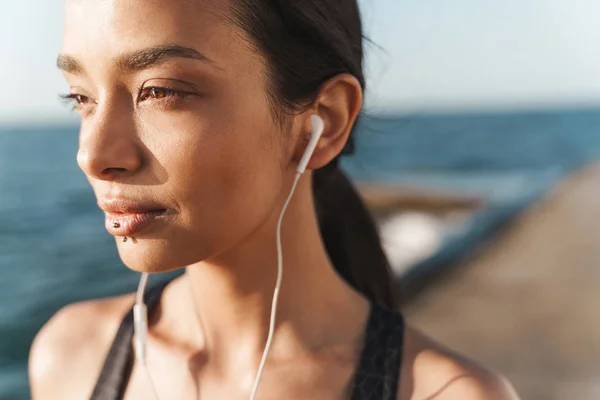 놀라운 강한 스포츠 여자 야외 해변에서 아침에 이어폰으로 음악을 듣고 포즈. — 스톡 사진