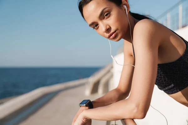 Bella bella seria donna sportiva forte all'aperto in spiaggia al mattino ascoltare musica con gli auricolari . — Foto Stock