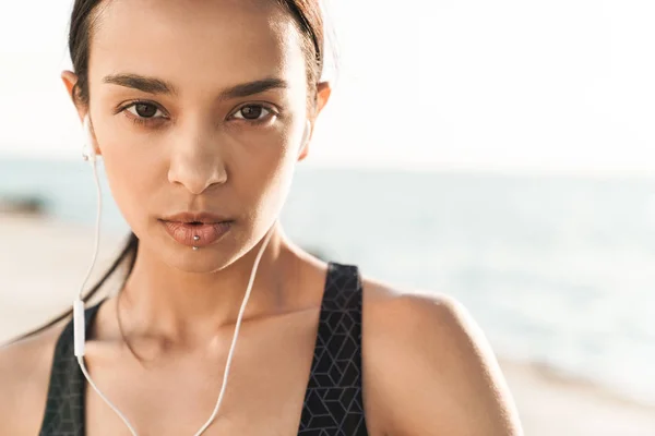 예쁘게 아름다운 심각한 강한 스포츠 여자 야외 해변에서 아침 에 듣는 음악 와 이어폰. — 스톡 사진