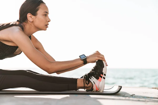 Genç güçlü fitness kadın sabah plajda açık havada germe egzersizleri yapmak. — Stok fotoğraf