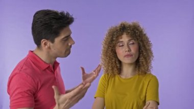 Yakışıklı genç adam kız arkadaşına bağırıyor. Güzel genç grimacing kadın agresif olma ve diz ile erkek arkadaşı isabet. Çekici genç çift izole mor arka plan üzerinde birbirleriyle tartışıyor