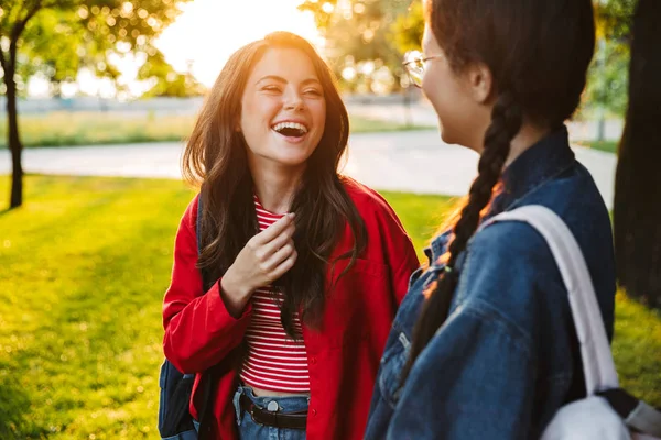 Beeld van twee lachende meisjes studenten praten en kijken naar elkaar tijdens het wandelen in Green Park — Stockfoto