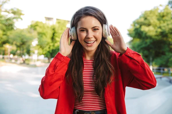 Image d'une étudiante rieuse écoutant de la musique avec des écouteurs sur un terrain de sport — Photo
