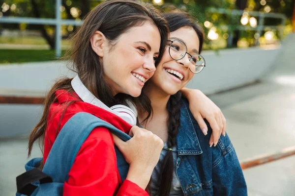 Immagine di due ragazze allegre che ridono e si abbracciano insieme mentre camminano nel parco — Foto Stock