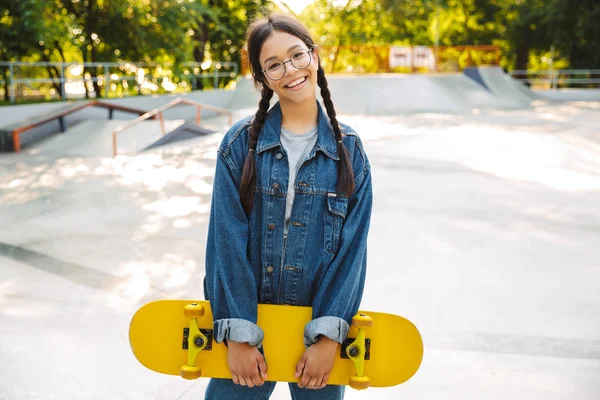 Beeld van vreugdevolle meisje glimlachend en verheuge terwijl het houden van skateboard in Skatepark — Stockfoto