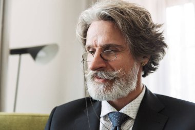 Ciddi yakışıklı gri saçlı üst düzey işadamı evde resmi giysiler gözlük giymiş kapalı.
