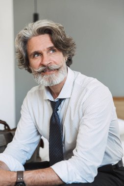 Neşeli mutlu kıdemli gri saçlı iş adamı evde kapalı yatakta oturan.