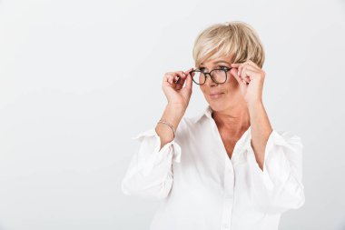 Gözlük tutan ve kameraya bakan memnun yetişkin kadın portresi