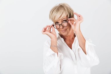 Gözlük tutan ve kameraya bakan çekici yetişkin kadının portresi