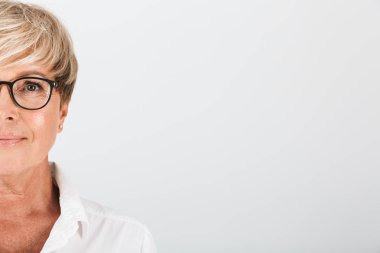 Kameraya bakan gözlük takan orta yaşlı bir kadının portresi kırpılmış