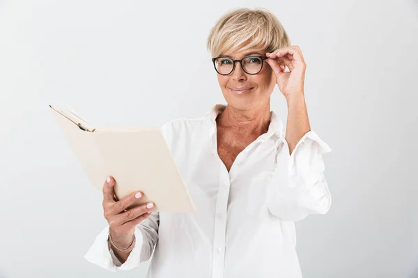 Portrait of charming adult woman wearing eyeglasses reading book — Stock Photo, Image