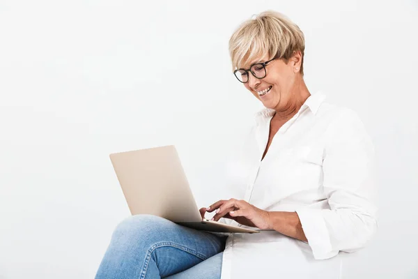 Изображение веселой взрослой женщины в очках, улыбающейся сидя — стоковое фото