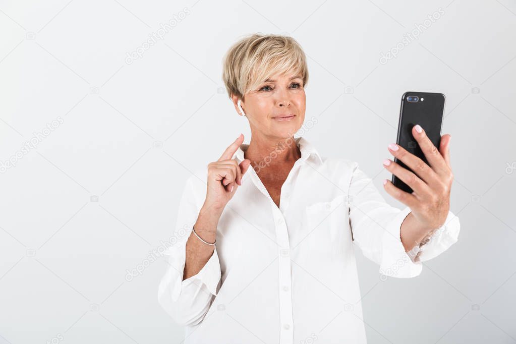 Portrait of pleased adult woman with short blond hair using earp