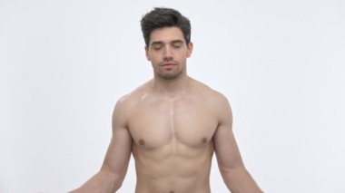 Çıplak gövde kapalı gözleri ile meditasyon ve beyaz arka plan izole üzerinde kameraya bakarken birlikte elleri koyarak sakin genç esmer adam