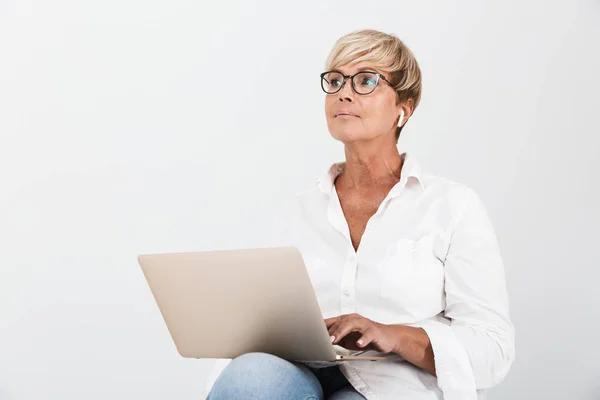 Зображення жінки середнього віку, яка носить окуляри та навушники сидіння — стокове фото