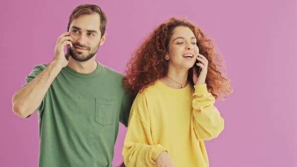 Mooie Gelukkige Jonge Paar Glimlachend Praten Hun Smartphones Roze Achtergrond — Stockvideo
