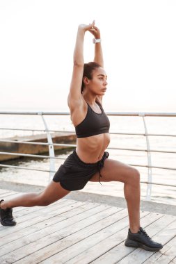 İnce genç kadın çömelme ve vücudunu germe görüntü whil