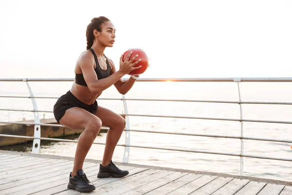 Imagem de mulher jovem agachando com bola de fitness enquanto fazendo wor — Fotografia de Stock