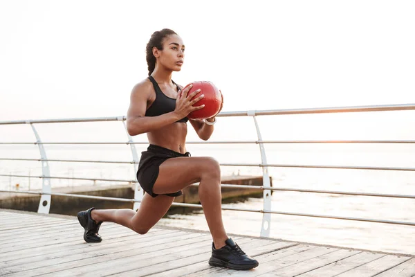 Imagem da mulher afro-americana agachada com bola de fitness enquanto — Fotografia de Stock