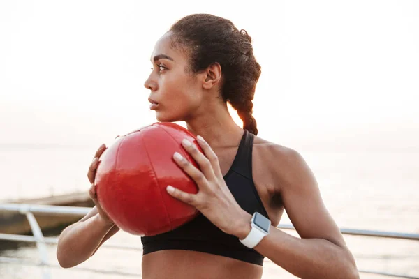 Imagem de mulher concentrada olhando de lado com bola de fitness enquanto — Fotografia de Stock