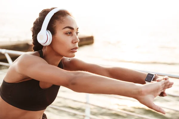 Imagen de una mujer sana enfocada con auriculares que estiran su bo — Foto de Stock