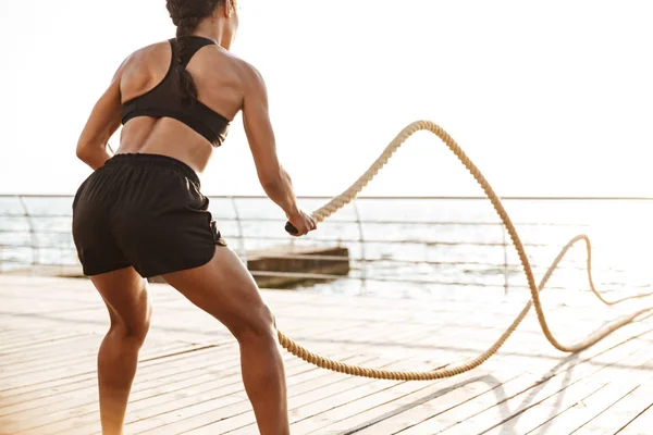 Imagen de una joven morena haciendo ejercicio con cuerdas de batalla — Foto de Stock