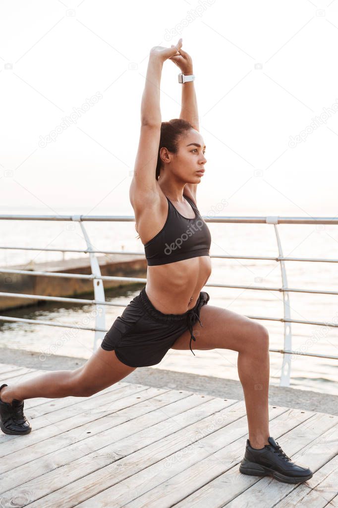 Image of slim young woman squatting and stretching her body whil