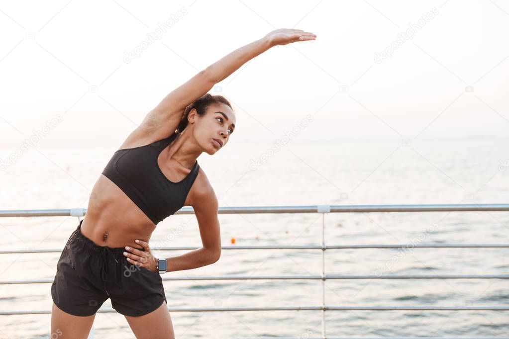 Image of attractive young woman stretching her body while doing 