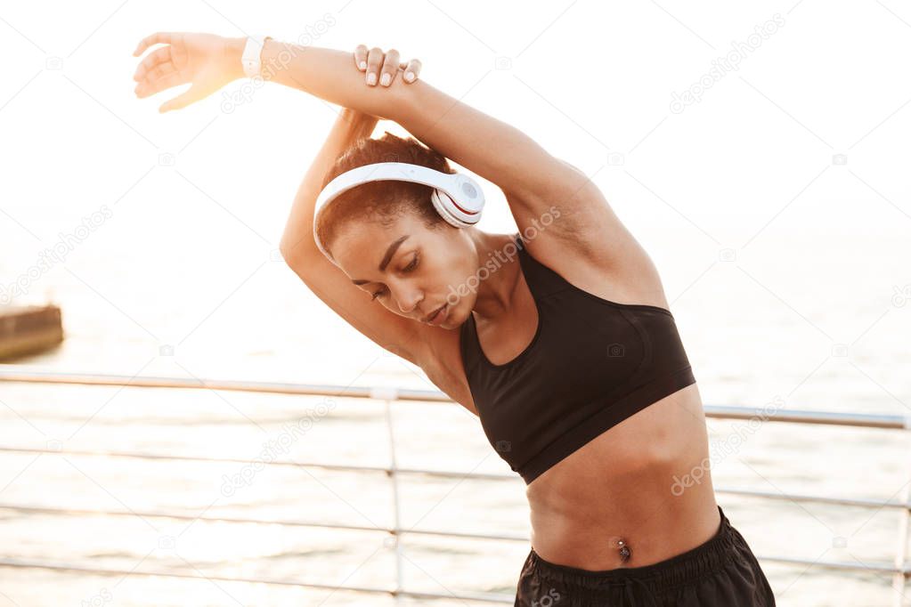 Image of attractive healthy woman with headphones stretching her