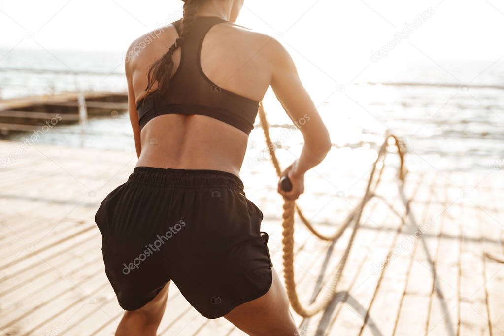 Cropped image of concentrated young woman doing workout with bat