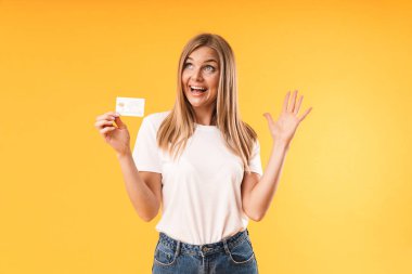 Kredi kartı tutarken gülümseyen rahat t-shirt giyen pozitif sarışın kadın Görüntü closeup