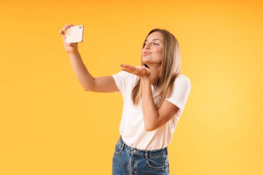 Akıllı telefonda selfie fotoğrafı çekerken hava öpücüğü üfleyen çekici sarışın kadının görüntüsü yakın çekimi