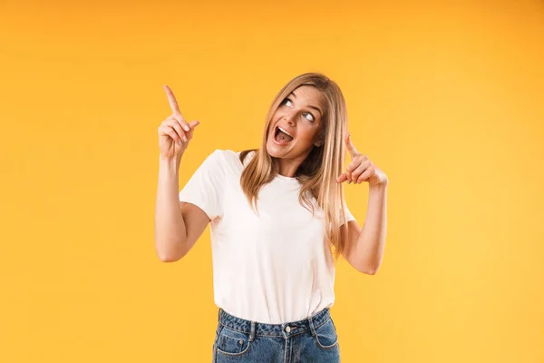 Image d'une jolie femme blonde portant un t-shirt décontracté souriant à la caméra et pointant du doigt le copyspace — Photo