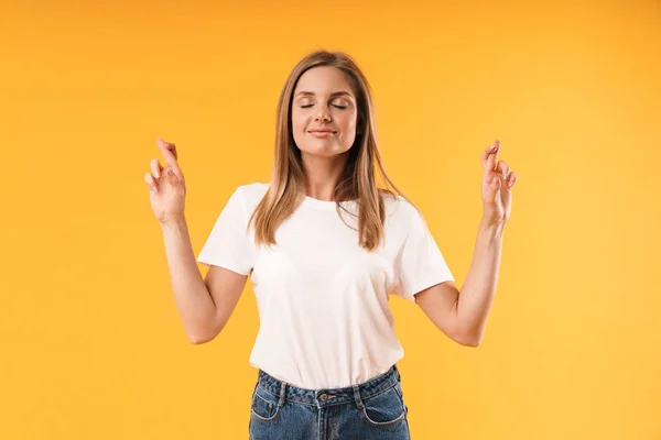 Imagem de mulher loira otimista vestindo camiseta casual sorrindo e mantendo os dedos cruzados — Fotografia de Stock